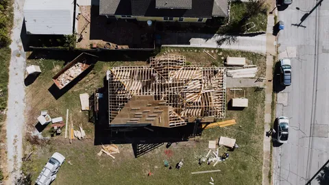 Aerial view of a wood-framed addition under construction next to an existing home