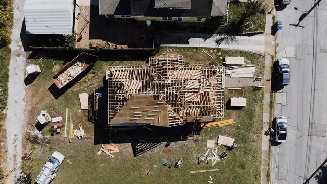 Aerial view of a wood-framed addition under construction next to an existing home