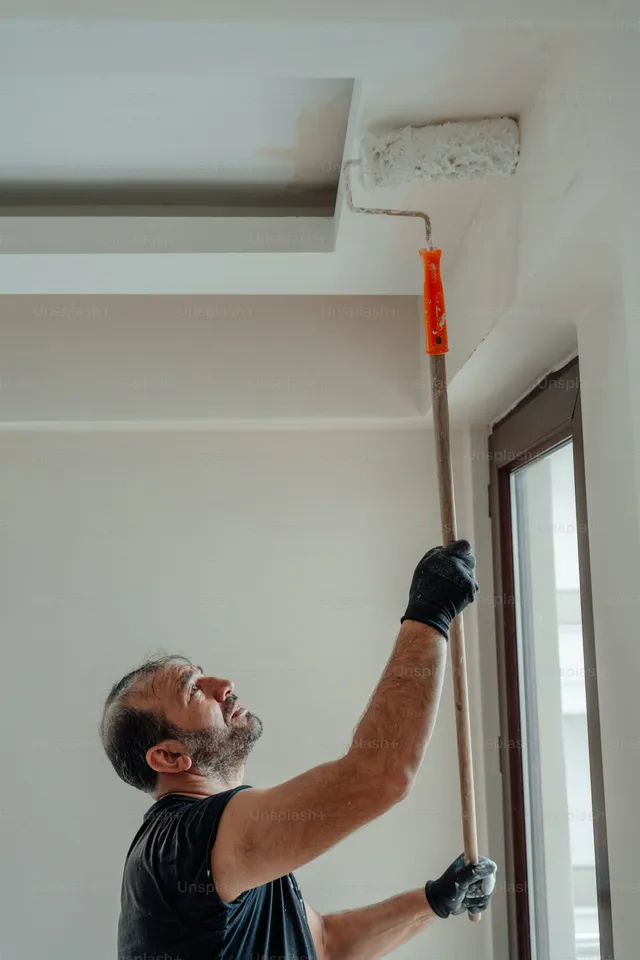 Painter working on ceiling trim